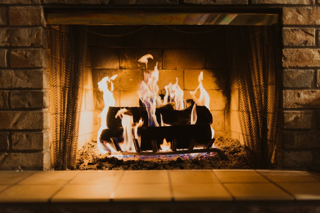 Feu de bois dans une cheminée en pierre avec rideau pare-étincelles