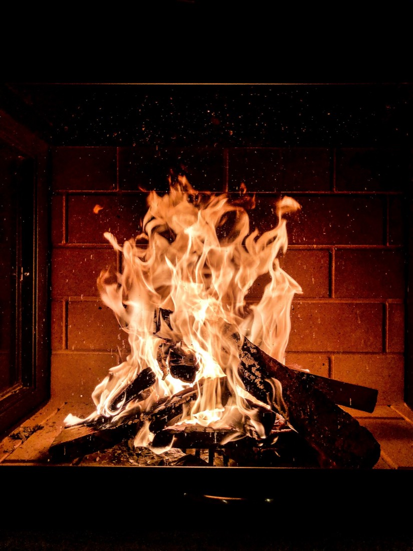 Flambée vive de bûches vue à travers la vitre d'un poêle